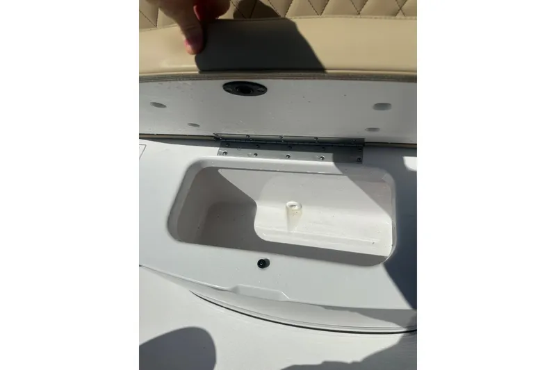Slide: The Image of 2026 Sportsman Open 232 Center Console boat storage compartment with beige cushioned seat. - 23