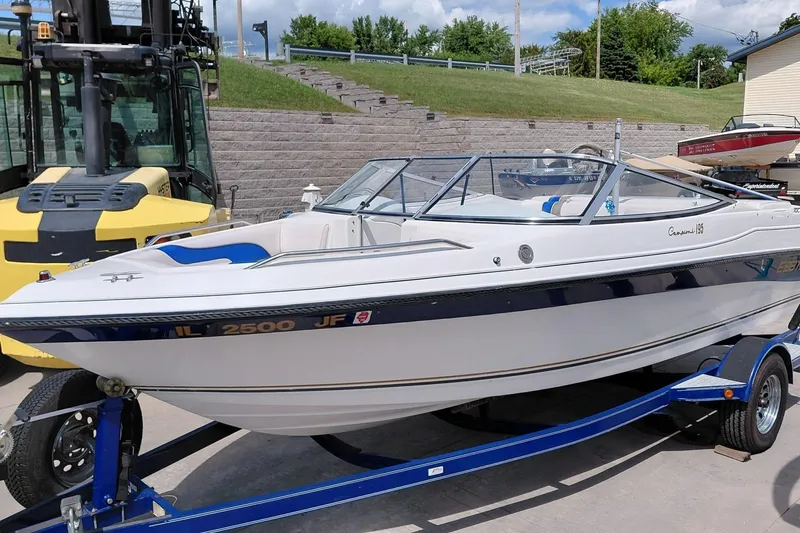Slide: The Image of 1999 Ebbtide Campione 190 boat on trailer, parked outdoors near forklift. - 2