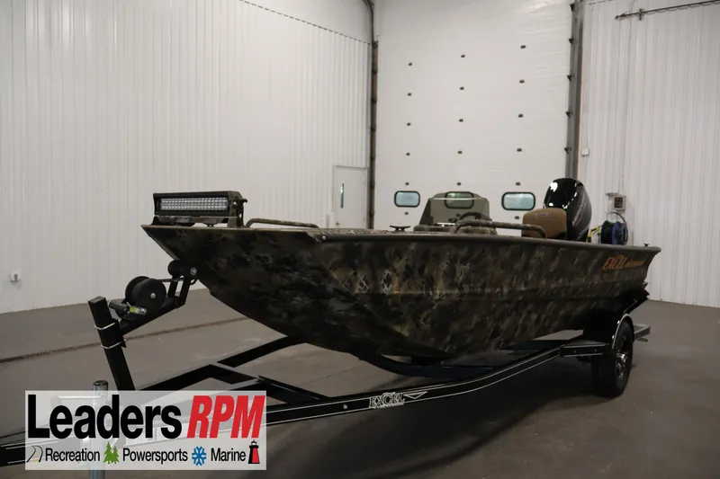 The Image of 2025 Excel 1651 River Warrior SC boat in a showroom, featuring camouflage design and trailer. - 1