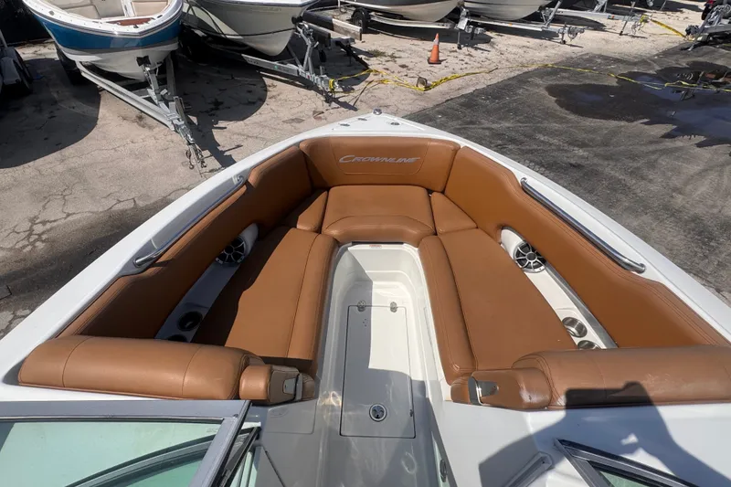 Slide: The Image of 2023 Crownline 250 XSS boat with tan seating, docked among other boats. - 6
