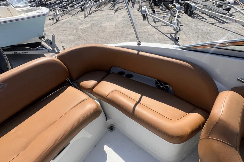 Slide: The Image of 2023 Crownline 250 XSS boat interior with tan leather seating and visible boat trailers. - 10