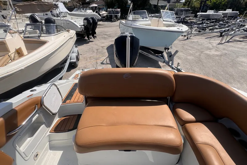 Slide: The Image of 2023 Crownline 250 XSS boat interior with tan leather seating, docked among other boats. - 9