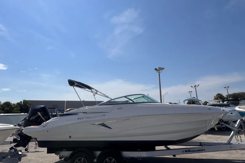 Slide: The Image of 2023 Crownline 250 XSS boat on trailer under clear blue sky. - 2