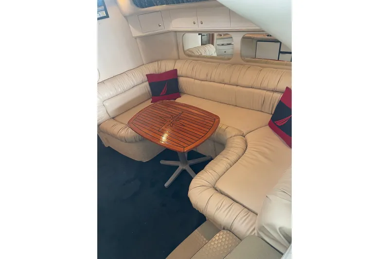 Slide: The Image of 1999 Sea Ray 370 Express Cruiser interior with beige seating and wooden table. - 18