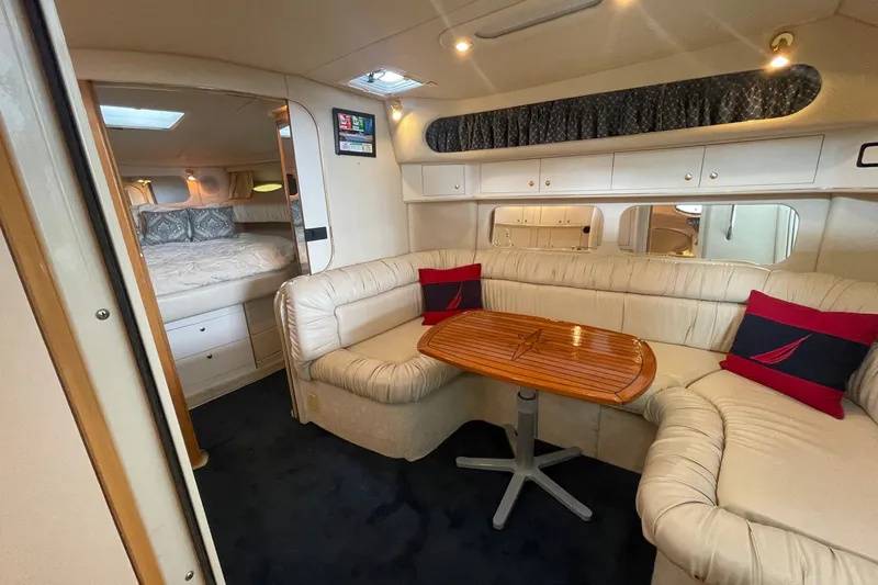 Slide: The Image of 1999 Sea Ray 370 Express Cruiser interior with cozy seating and wooden table. - 17