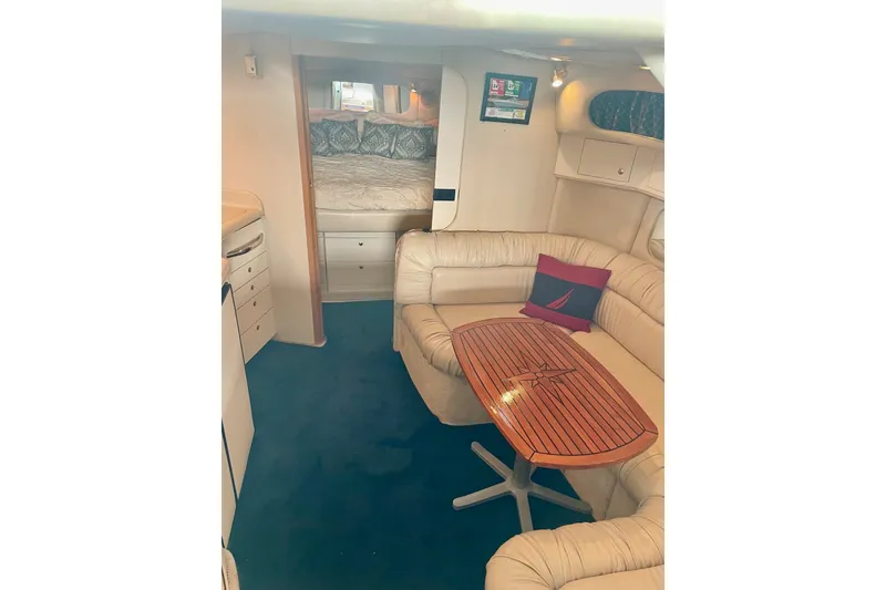 Slide: The Image of Interior of 1999 Sea Ray 370 Express Cruiser with cozy seating and wooden table. - 21