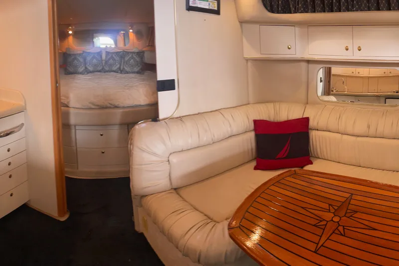 Slide: The Image of Interior of 1999 Sea Ray 370 Express Cruiser with cozy seating and elegant wood table. - 24