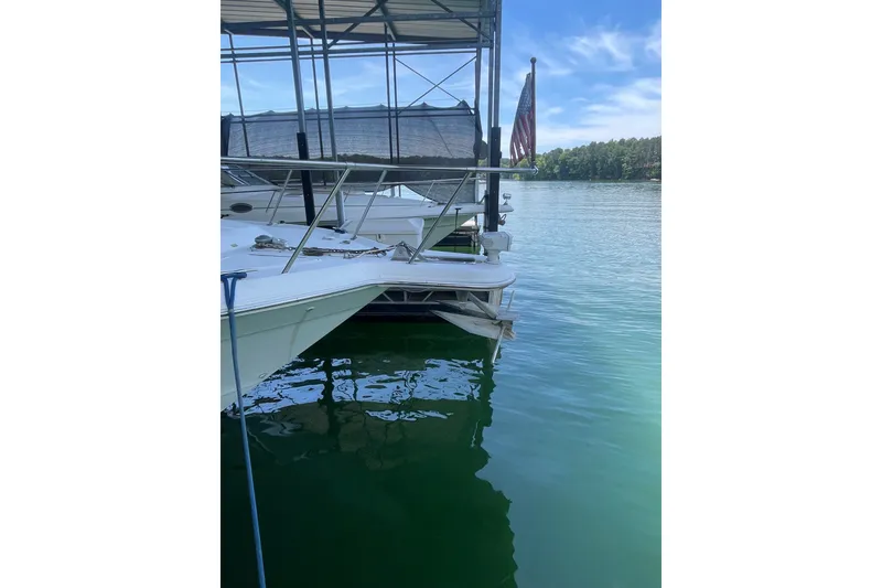 Slide: The Image of 1999 Sea Ray 370 Express Cruiser docked on a serene lake with clear skies. - 31