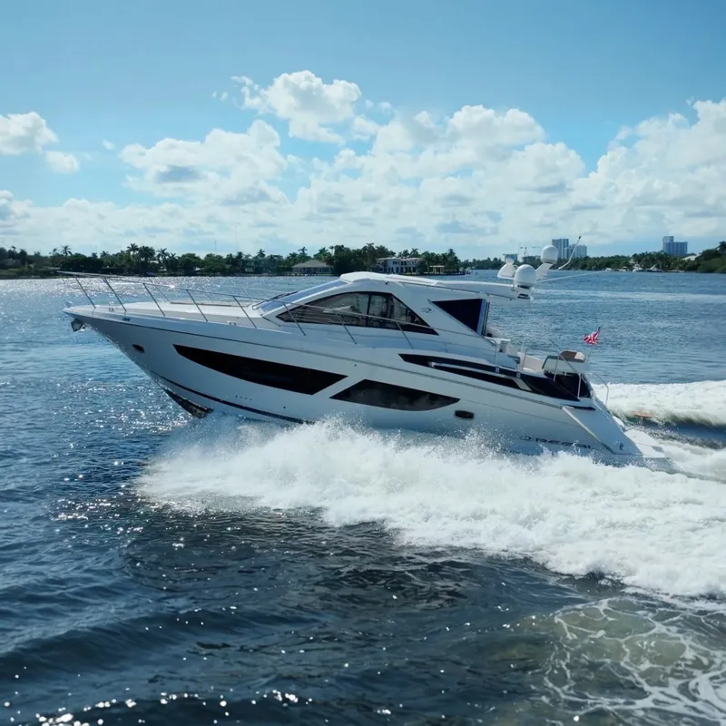 The Image of 2017 Regal 53 Sport Coupe yacht cruising on a sunny day, creating waves. - 0