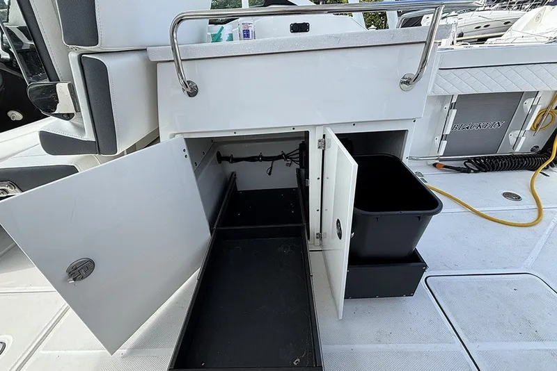 Slide: The Image of 2023 Blackfin 272 DC boat storage compartments with open doors and visible trash bin. - 12