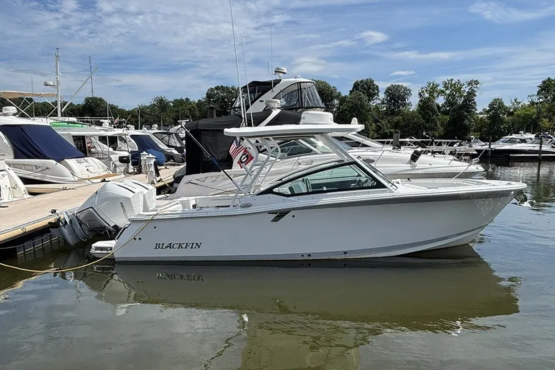 The Image of 2023 Blackfin 272 DC boat docked at a marina under a clear sky. - 1