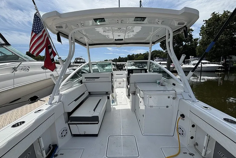 Slide: The Image of 2023 Blackfin 272 DC boat interior with seating and American flag, docked at marina. - 4