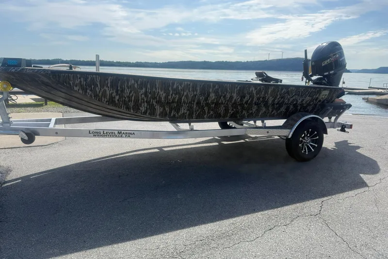 The Image of Avid 18 Commander 2027 boat on trailer by a lake, sunny day. - 1