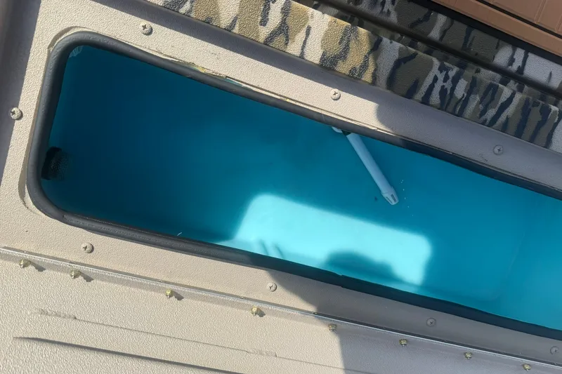 Slide: The Image of Open storage compartment in 2027 Avid 18 Commander boat, featuring blue interior and camouflage trim. - 15