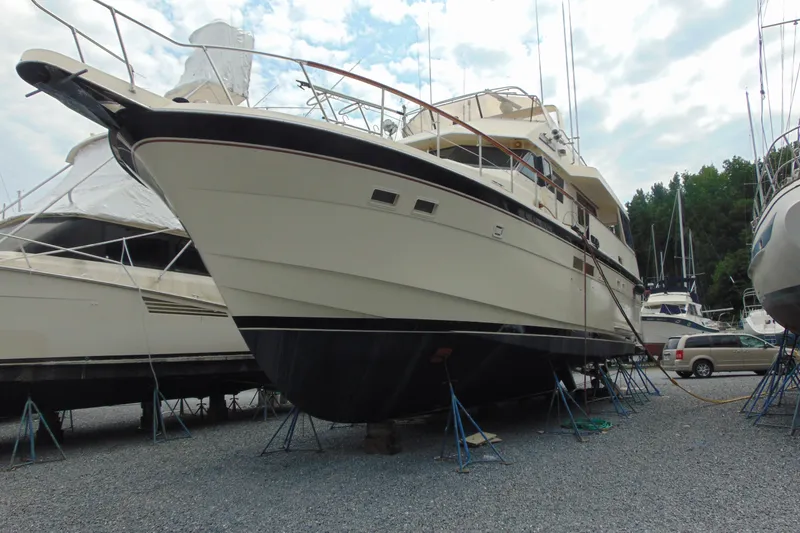 The Image of 1987 Hatteras 54 Motor Yacht on stands in a boatyard, surrounded by other vessels. - 0