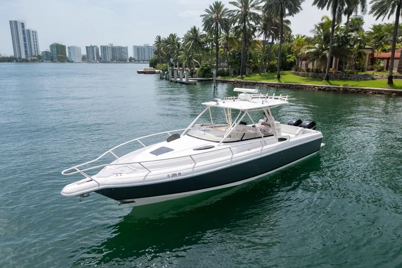 Slide: The Image of 2006 Intrepid 348 Walkaround boat cruising near palm-lined shore and city skyline. - 9