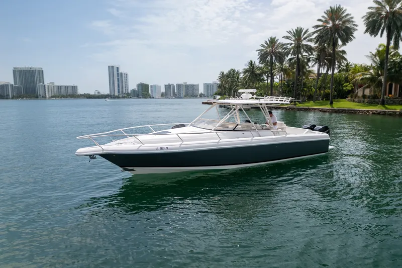 Slide: The Image of 2006 Intrepid 348 Walkaround boat on calm water with city skyline and palm trees. - 2