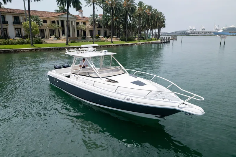 Slide: The Image of 2006 Intrepid 348 Walkaround boat cruising near waterfront estate with palm trees. - 3