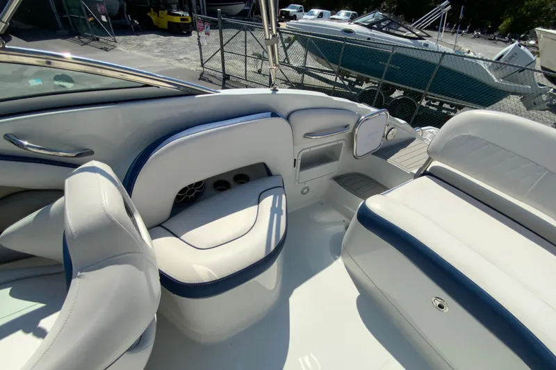 Slide: The Image of 2019 Crownline Eclipse E235 XS boat interior with white and blue seating, docked outdoors. - 14