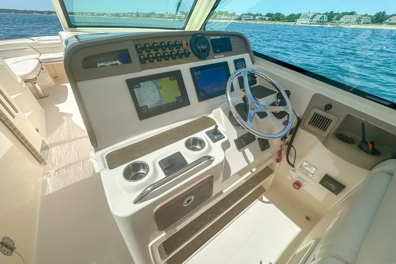 Slide: The Image of 2015 Grady-White Freedom 375 helm with navigation screens, steering wheel, and ocean view. - 17