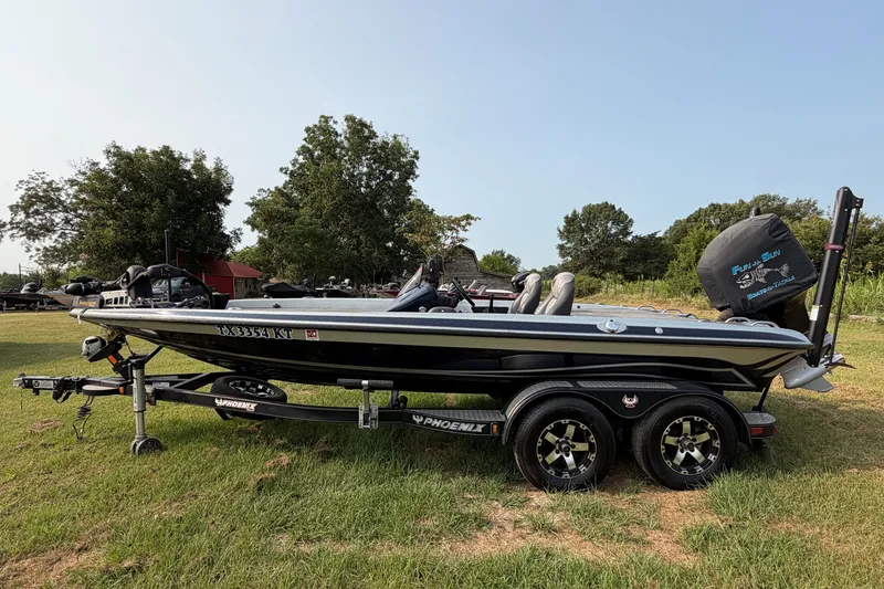 Slide: The Image of 2016 Phoenix 919 ProXP bass boat on trailer, parked on grass with trees in background. - 2
