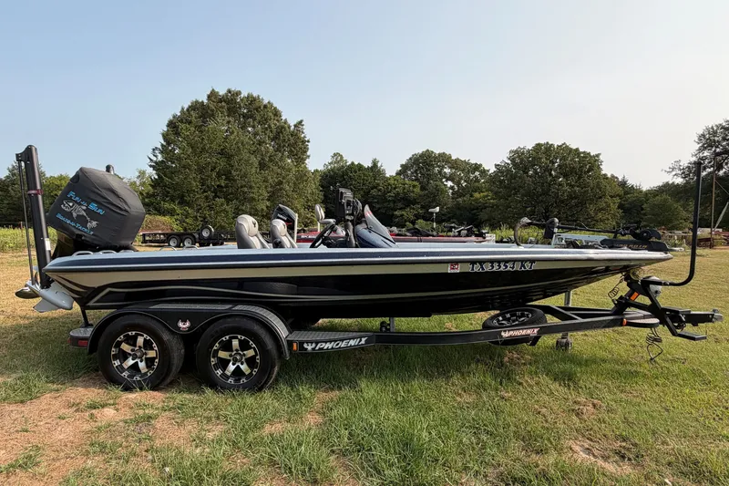 Slide: The Image of 2016 Phoenix 919 ProXP boat on trailer, parked on grass with trees in background. - 1
