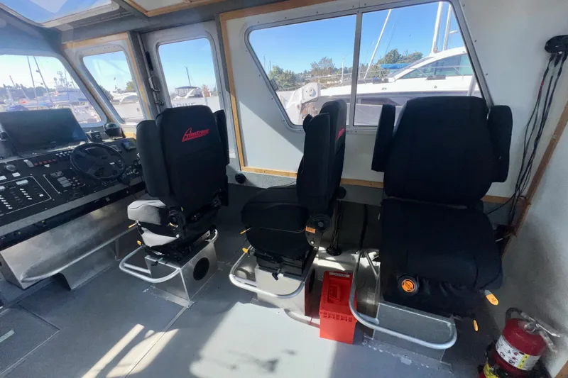 Slide: The Image of Interior of 2019 Armstrong Marine 38 Monohull Aluminum boat with three black seats and control panel. - 14