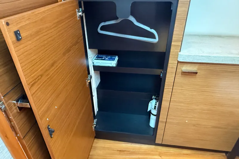 Slide: The Image of Open wooden cabinet with shelves, hanger, and fire extinguisher on Tiara Yachts Q44, 2016 model. - 29