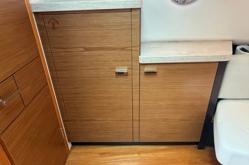 Slide: The Image of Wooden cabinetry inside a 2016 Tiara Yachts Q44, featuring sleek handles and a light countertop. - 27