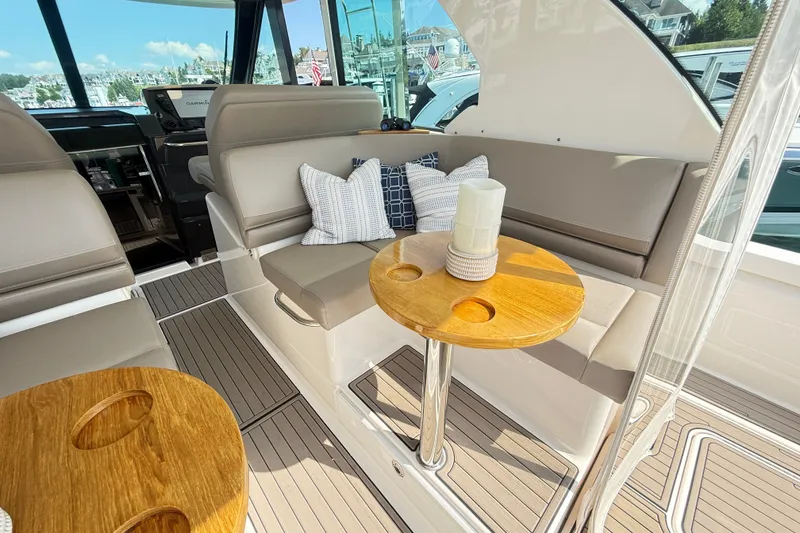 Slide: The Image of 2016 Tiara Yachts Q44 interior with cushioned seating and wooden table, featuring nautical decor. - 14
