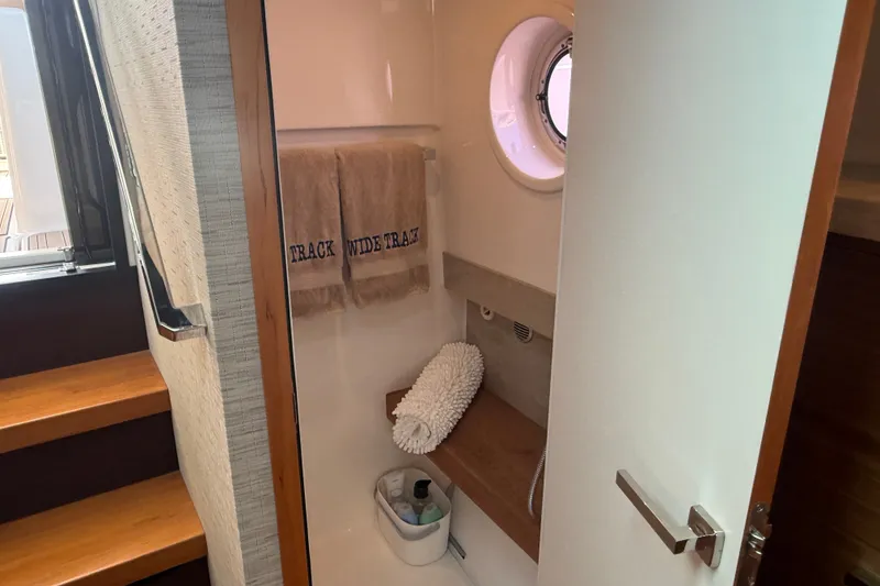 Slide: The Image of 2016 Tiara Yachts Q44 bathroom with towels, porthole, and wooden accents. - 30
