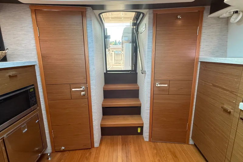 Slide: The Image of Interior of 2016 Tiara Yachts Q44 with wooden cabinetry and stairs leading outside. - 32