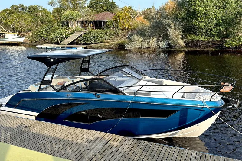 Slide: The Image of Blue Hanover 327 boat docked on a serene river, surrounded by lush greenery, 2026 model. - 2