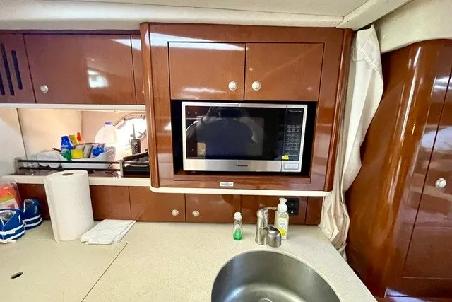 Slide: The Image of 2008 Sea Ray Sundancer 330 galley with microwave, sink, and wooden cabinetry. - 23