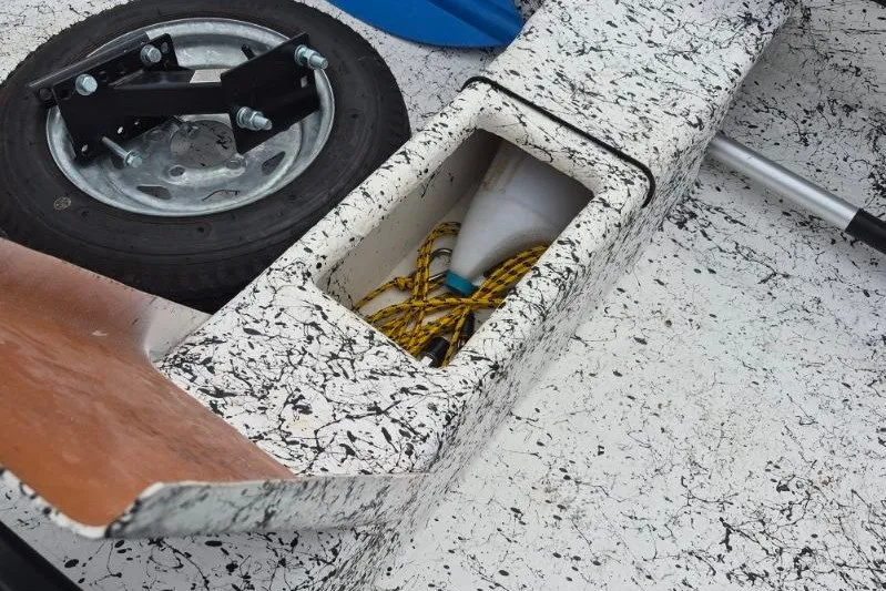 Slide: The Image of 2022 Gheenoe NMZ 15.4 boat interior with storage compartment and trailer wheel. - 12