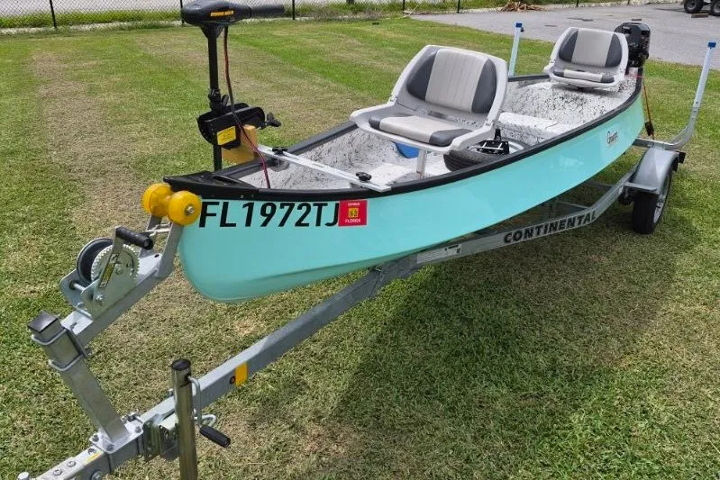Slide: The Image of 2022 Gheenoe NMZ 15.4 boat on trailer, light blue, parked on grass. - 2