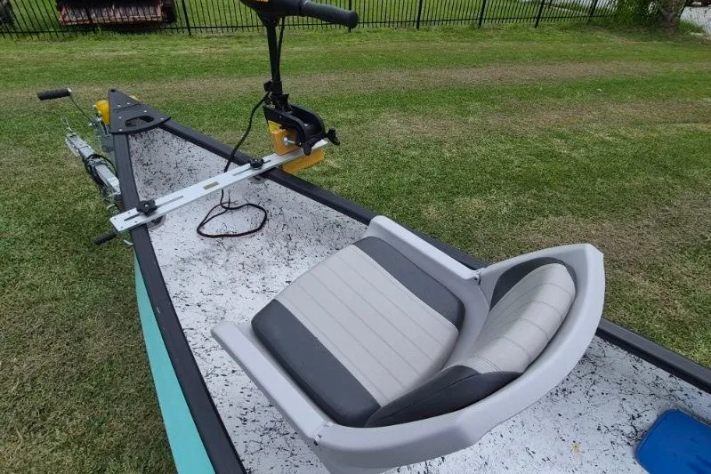 Slide: The Image of 2022 Gheenoe NMZ 15.4 boat with motor and cushioned seat on grassy area. - 11