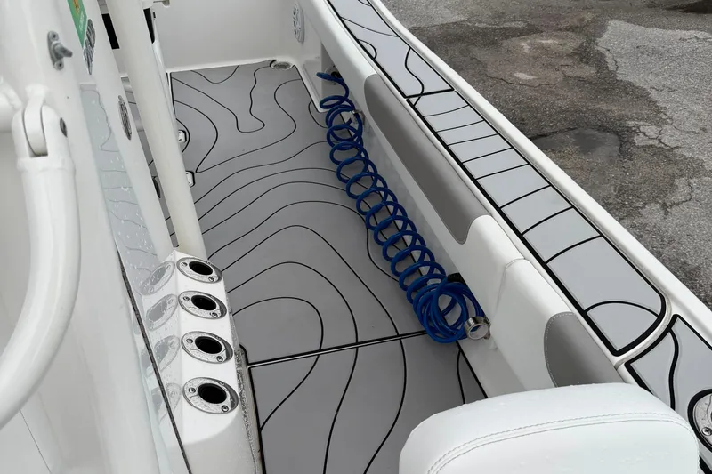 Slide: The Image of 2023 Caymas 26 HB boat interior with rod holders and coiled blue hose. - 14
