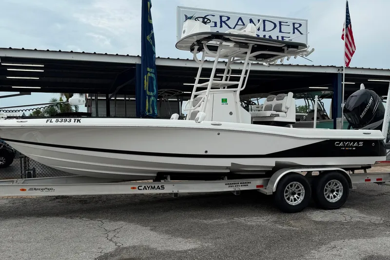 The Image of 2023 Caymas 26 HB boat on trailer at dealership, featuring sleek design and Mercury engine. - 0