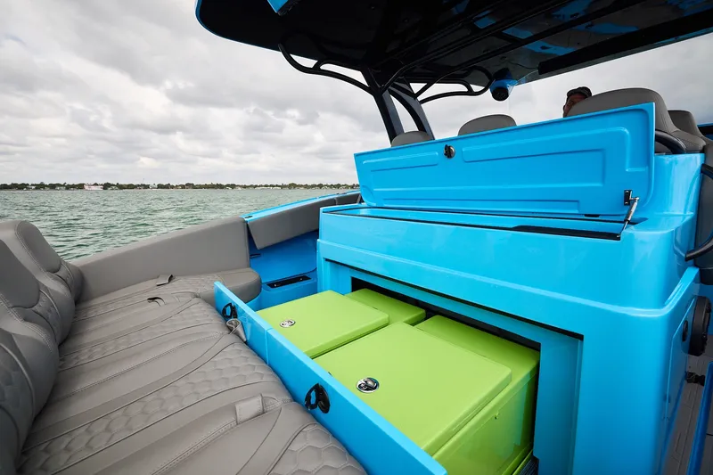 Slide: The Image of Midnight Express 43 Open boat with vibrant blue and green storage compartments on a calm sea. - 17
