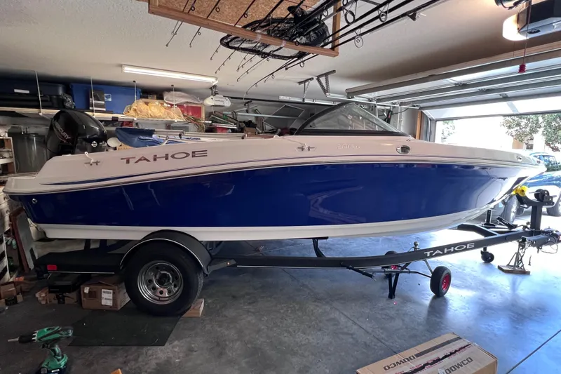 The Image of 2024 Tahoe 200 S boat in garage, blue and white design, on trailer. - 0