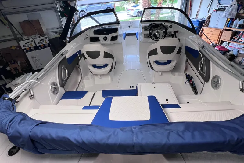 Slide: The Image of 2024 Tahoe 200 S boat interior with blue and white seating in a garage setting. - 15