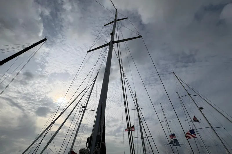 Slide: The Image of Tall sailboat masts against a cloudy sky, featuring American flags, Caliber 40LRC 2002. - 4