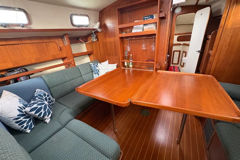 Slide: The Image of Cozy 2002 Caliber 40LRC yacht interior with wooden dining table and cushioned seating. - 34