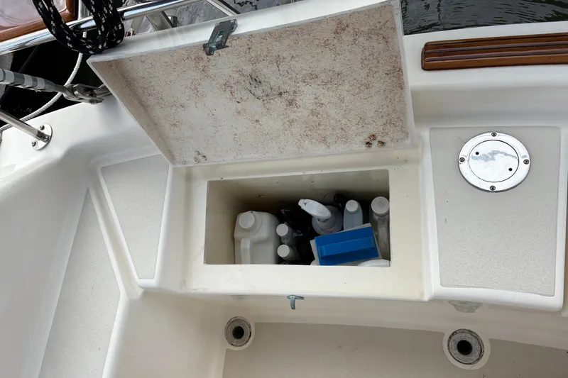 Slide: The Image of Open storage compartment on 2002 Caliber 40LRC boat, containing various bottles and cleaning supplies. - 48