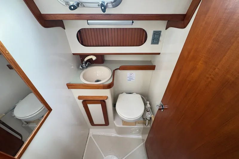 Slide: The Image of Compact bathroom in a 2002 Caliber 40LRC yacht with sink, toilet, and wooden accents. - 36