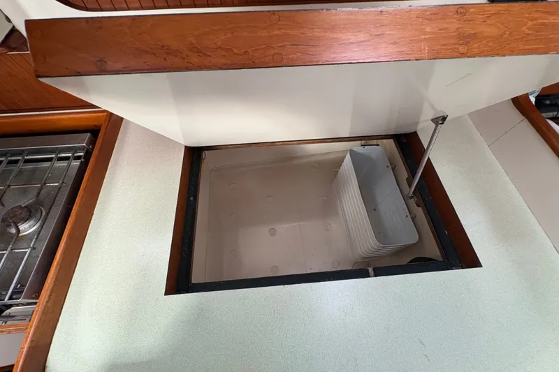 Slide: The Image of Open storage compartment in 2002 Caliber 40LRC yacht kitchen, featuring wooden and metal elements. - 26