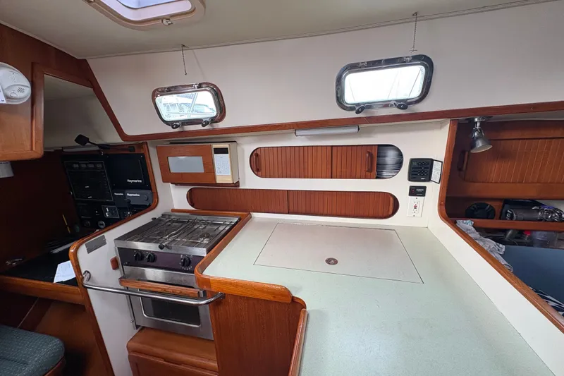 Slide: The Image of 2002 Caliber 40LRC yacht kitchen with stove, microwave, and wooden cabinetry. - 25