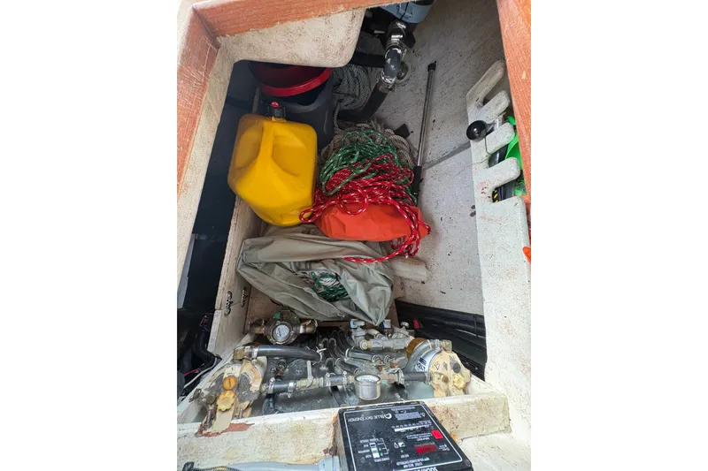 Slide: The Image of Storage compartment of 2002 Caliber 40LRC boat with ropes, fuel can, and equipment. - 50