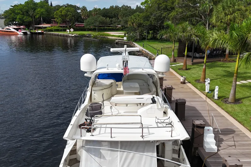 Slide: The Image of 2008 Azimut 62E yacht docked by a lush, palm-lined waterfront. - 64